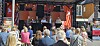 Panel på en utendørsscene foran et sittende publikum.