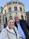 To smilende personer foran en rikt utsmykket historisk kirke.